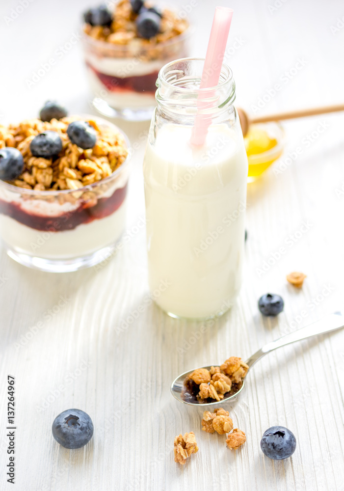 Fitness breakfast with muesli, honey and milk on white table Fitness breakfast with muesli, honey and milk on white table