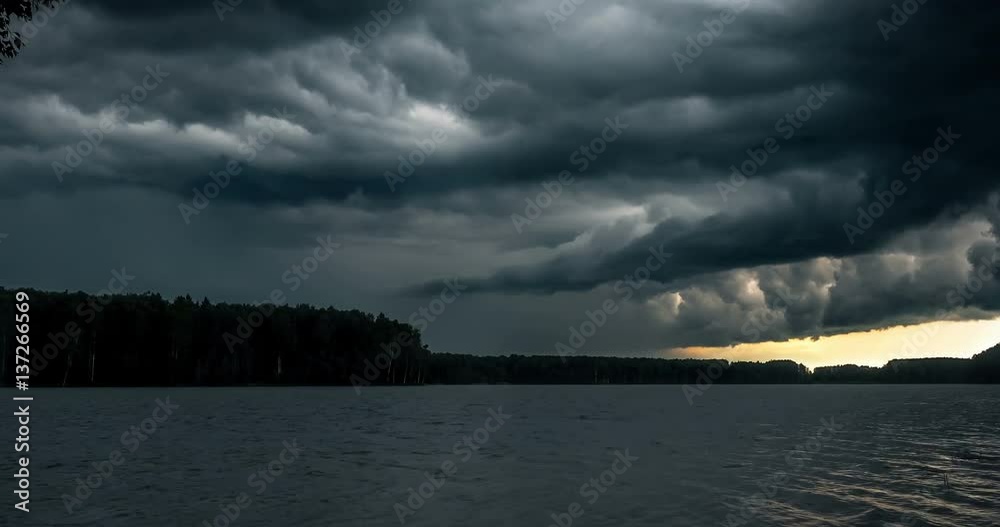 Dark stormy clouds float across the sky. Storm mooving over the river. Time lapse of storm clouds moving fast