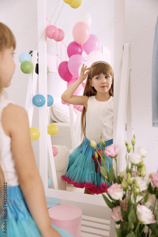 Obraz premium Cute birthday girl looking in mirror at home