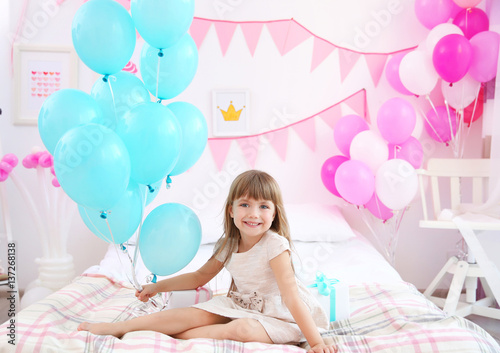 Cute girl with balloons sit...