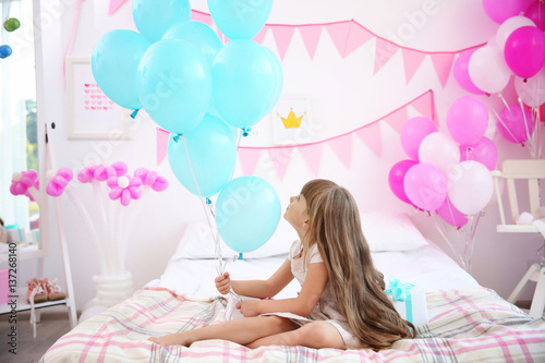 Cute girl with balloons sit...