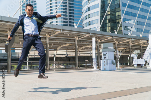 Young businessman jumping with joy in success. Focus is on the left