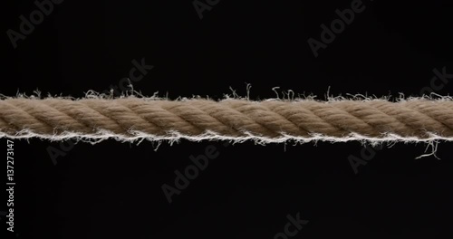 Close shot of rope being pulled across the frame against black