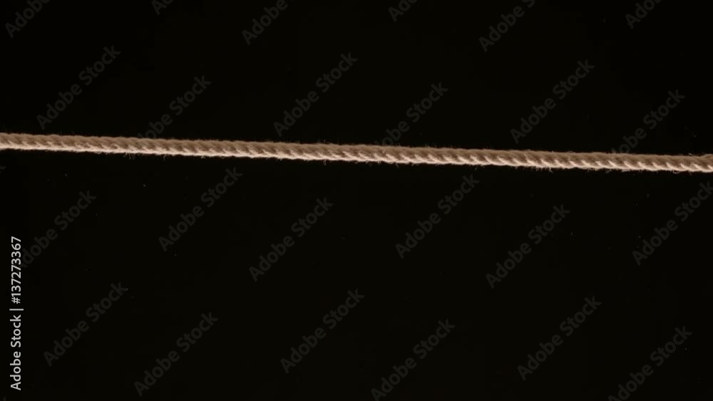 Length of rope being pulled tight across frame against black Length of rope being pulled tight across frame against black