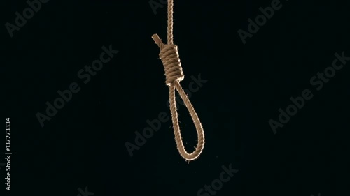 Hang mans noose falling into frame against black background