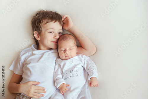 Photographie older brother hugging his newborn sister