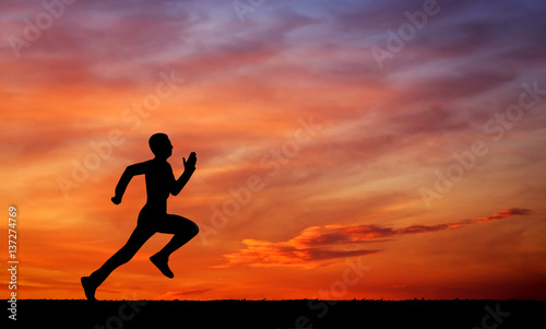 Silhouette of running man on sunset fiery sky background
