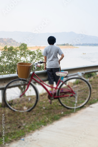 Vintage red bicycle beside river road
