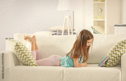 Little girl with book lying...
