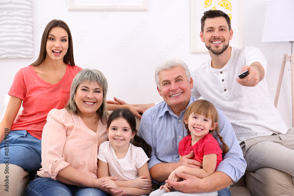 Happy family watching TV on sofa at home