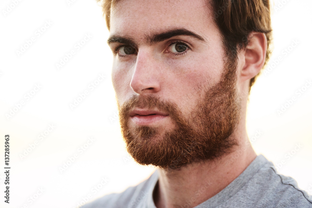 close up face shot of white bearded male looking straight into camera with serious facial expression.