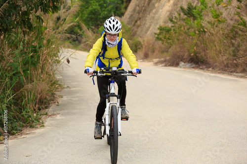 young woman riding mountain bike on forest trail