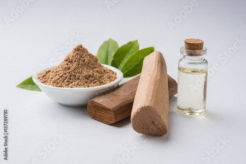 Chandan or sandalwood powder with traditional mortar, sandalwood sticks, perfume or oil and green leaves. selective focus photo