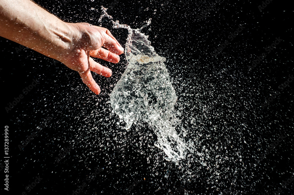 Burst of a balloon filled with water on black background