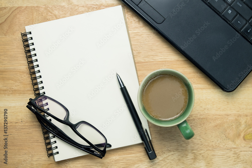 Notebook or note pad,smart phone,cup of coffee and glasses on Brown wooden background top view with copy space. office desk concept Notebook or note pad,smart phone,cup of coffee and glasses on Brown wooden background top view with copy space. office desk concept