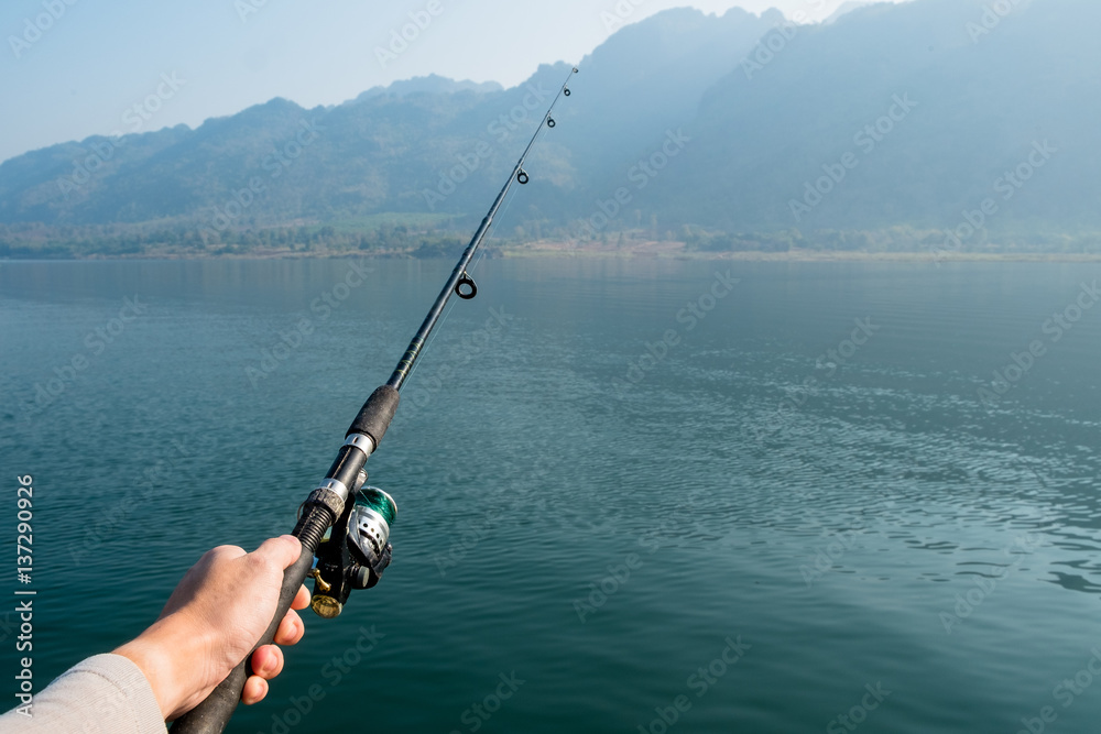 man holding fishing rod, fishing pole over the lake. man holding fishing rod, fishing pole over the lake.