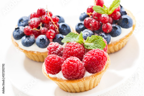 mini tarts with cream and fresh berries on white background, closeup