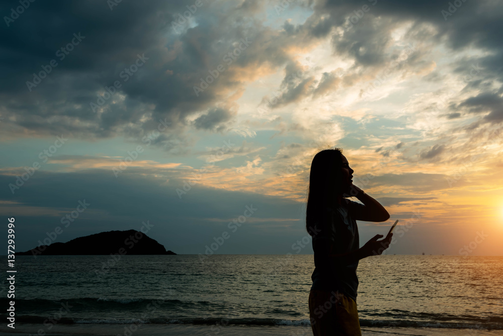 Fototapeta premium Silhouette women watching the sunset at the beach.