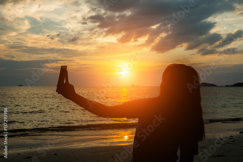 silhuoette women selfie and sunset on the beach seaside. photo