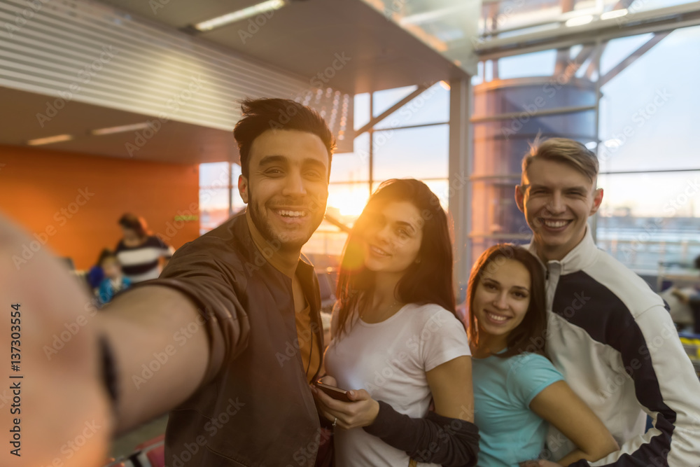 Fototapeta premium Young People Group In Airport Lounge Waiting Departure Happy Smile Mix Race Friends Taking Selfie Photo Flight