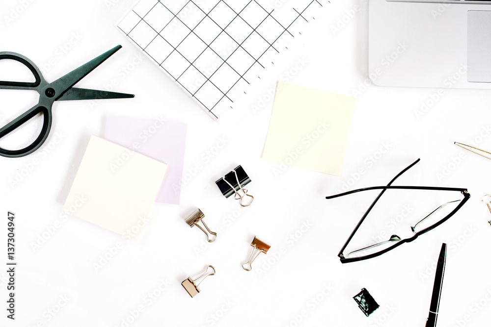 White office desk frame with paper blank and supplies. Laptop, notebook, scissors, pen, clips, glasses and office supplies on white background. Flat lay, top view, mockup. White office desk frame with paper blank and supplies. Laptop, notebook, scissors, pen, clips, glasses and office supplies on white background. Flat lay, top view, mockup.