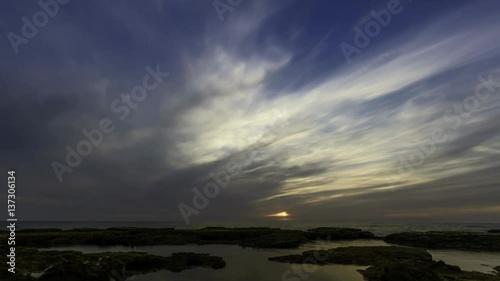 4k time lapse of clouds crossing the amazing sky over the sea or ocean at sunset. transition from day to night. The clouds cross slowly from left to right colored yellow orange purple blue.