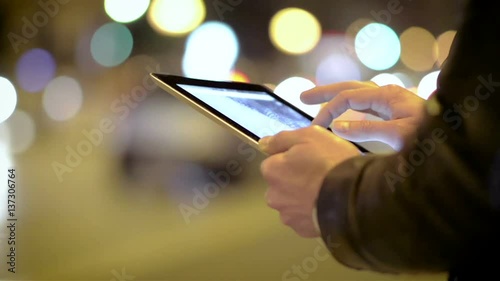 Close-Up of a Young Man Using a Tablet in the Night City