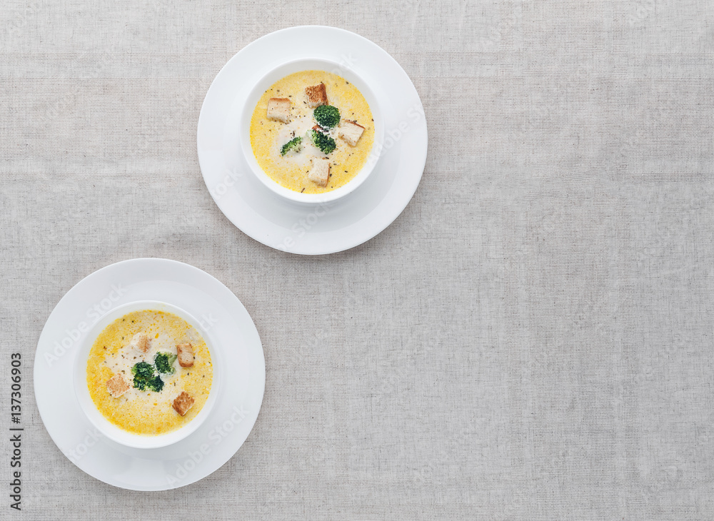 cheese soup with broccoli in a white plate on a white linen tablecloth cheese soup with broccoli in a white plate on a white linen tablecloth