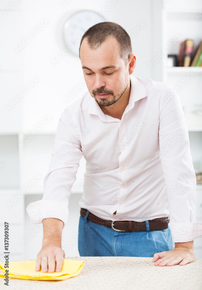 Positive young man cleaning office desk Positive young man cleaning office desk
