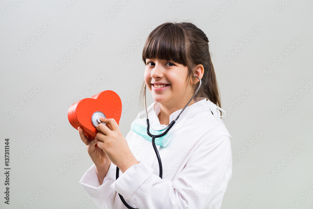 Beautiful little cardiologist holding heart shape and stethoscope. Beautiful little cardiologist holding heart shape and stethoscope.