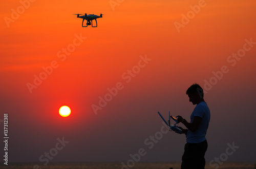 Man operating of flying drone quadrocopter at sunset © Glebstock