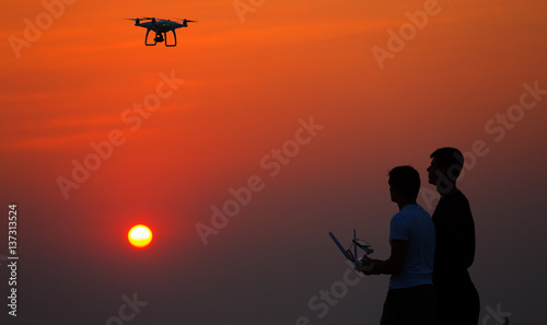 Man operating of flying drone quadrocopter at sunset