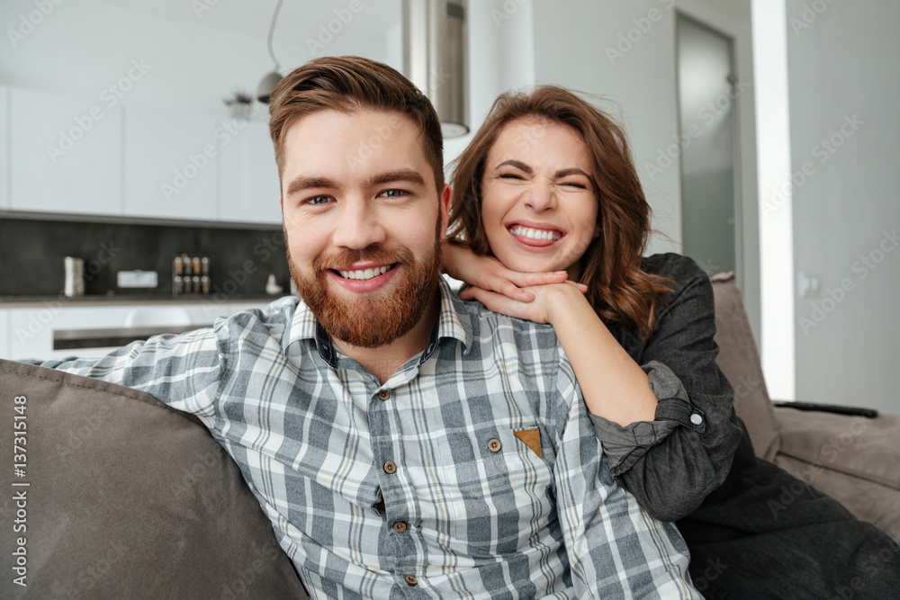 Young funny loving couple sitting on sofa indoors Young funny loving couple sitting on sofa indoors