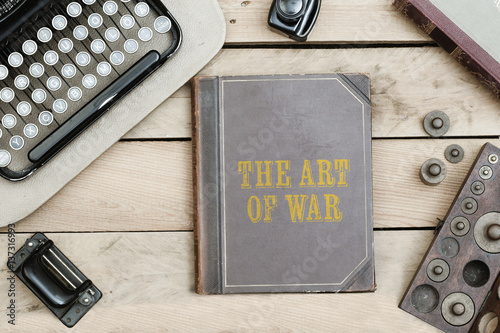 Obraz na płótnie The Art of War on old book cover at office desk with vintage items w salonie