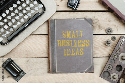 Small Business Ideas on old book cover at office desk with vintage items photo