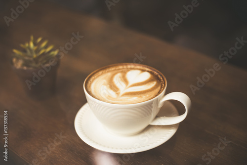 Vintage color tone of coffee latte art on wooden table in coffee shop.