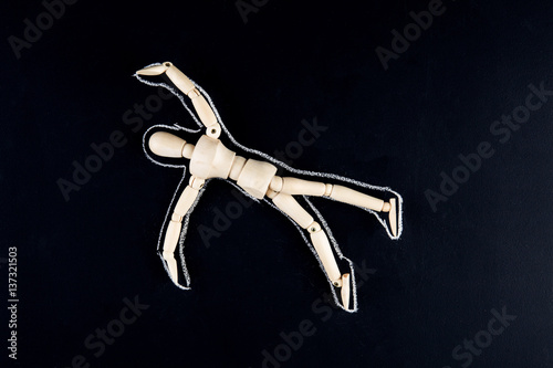 Wooden dummy figurine laying on the floor with chalk outline - crime or suicide concept.