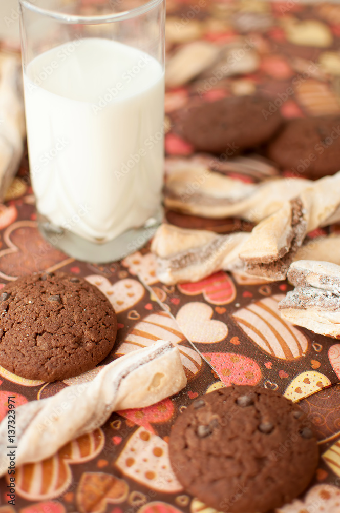 Fototapeta premium Glass of milk and cookies on dark napkin with image of hearts