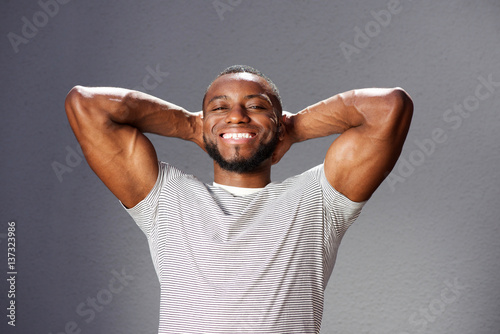 handsome muscular man smiling with hands behind head