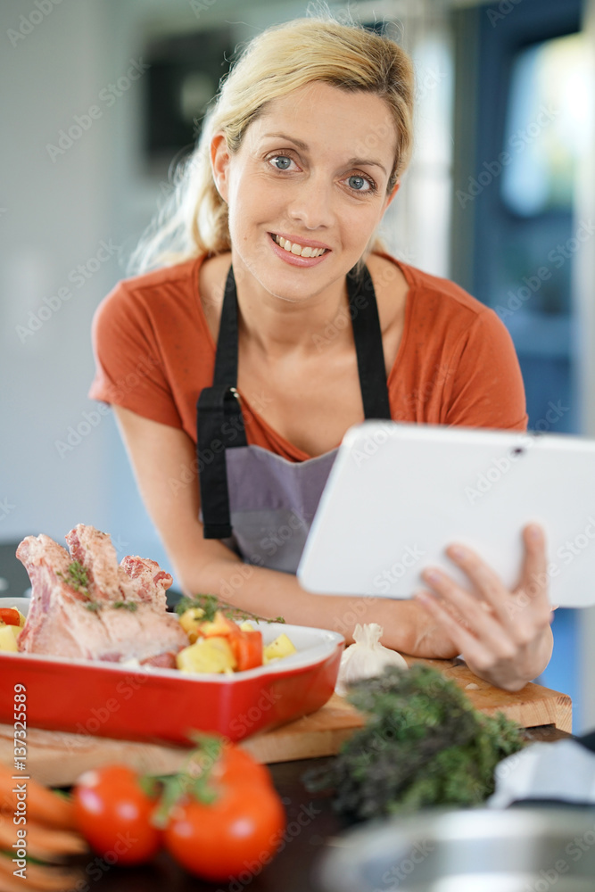 Woman in domestic kitchen reading cooking receipe on tablet Woman in domestic kitchen reading cooking receipe on tablet