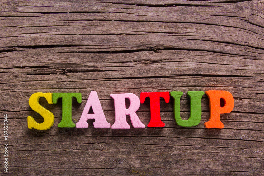 Fototapeta premium startup word made from colored wooden letters on an old table. Concept