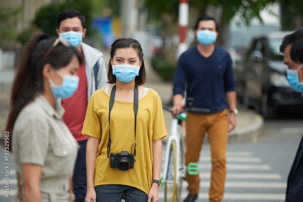 Danger of epidemic: Asian people wearing protective masks while crossing road in city center
