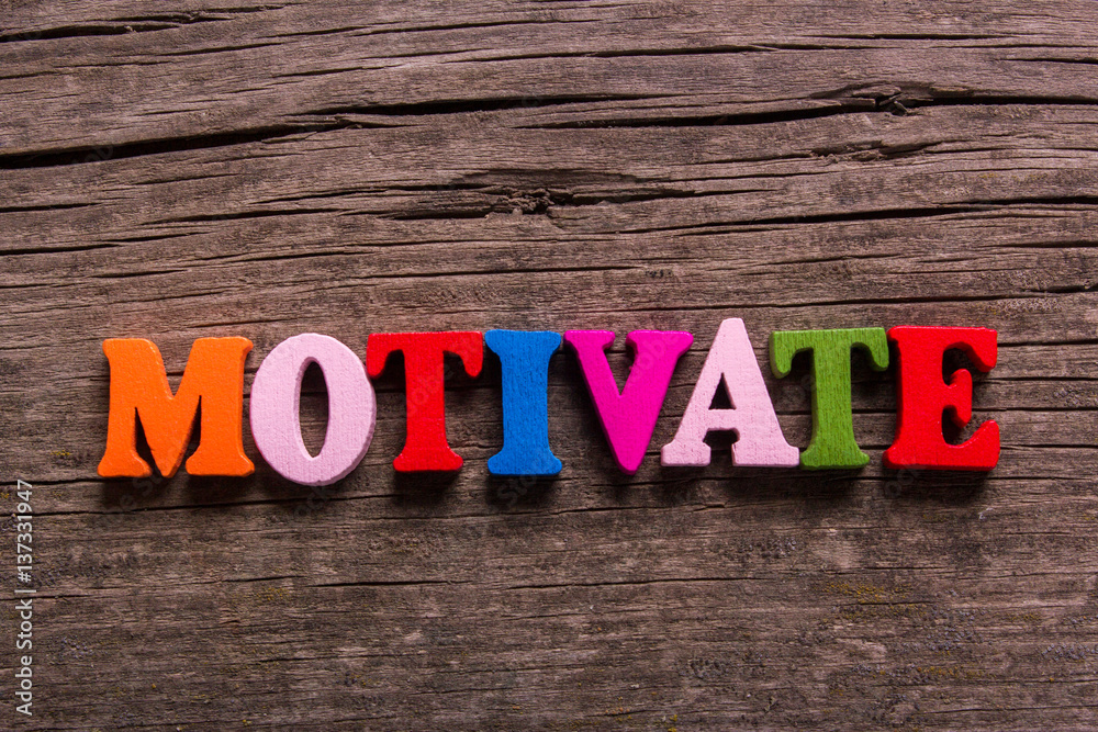 Naklejka premium motivate word made from colored wooden letters on an old table. Concept
