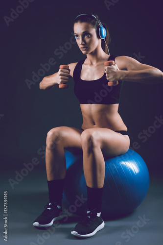 Fitness sporty woman training ,pumping up muscles with dumbbells on black background