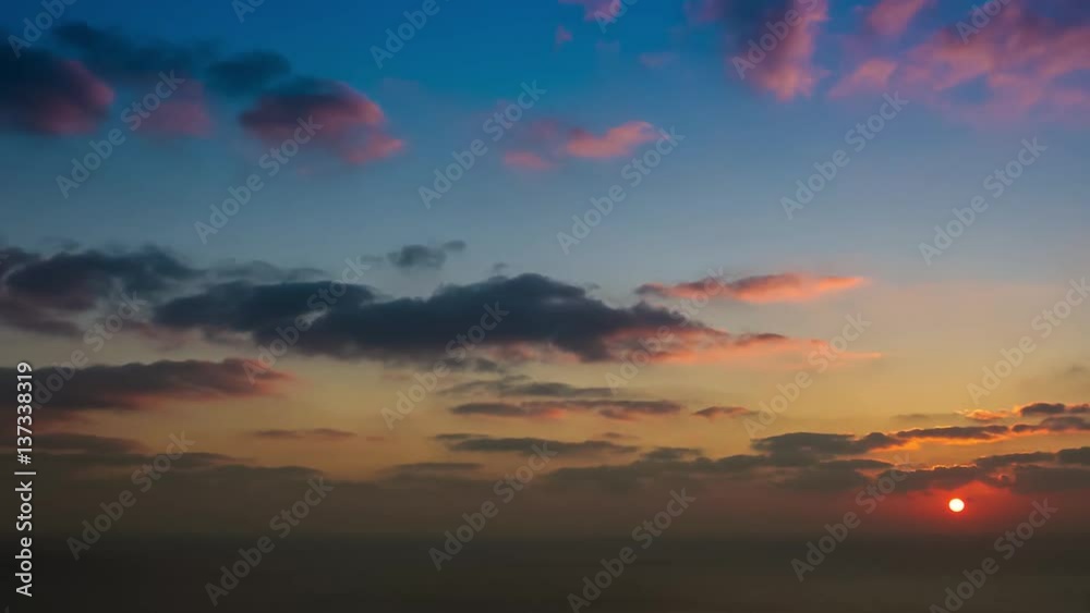 time lapse of clouds crossing the amazing sky over the sea or ocean at sunset. transition from day to night. The clouds cross slowly from left to right colored yellow orange purple blue