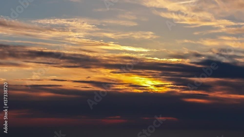 time lapse of clouds crossing the amazing sky over the sea or ocean at sunset. transition from day to night. The clouds cross slowly from left to right colored yellow orange purple blue