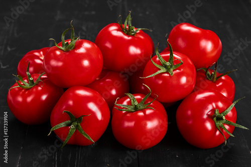 Tomato on a black background with realistic reflection and water drops. Fresh tomatoes