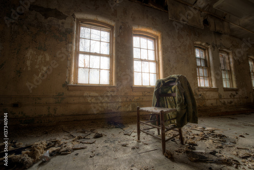 Old suit coat hanging on a chair in an abandoned room