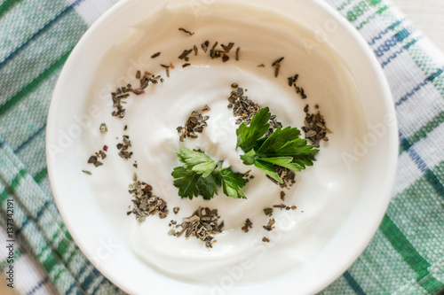 Greek yogurt with basil and parsley. White wooden background.
Top view.