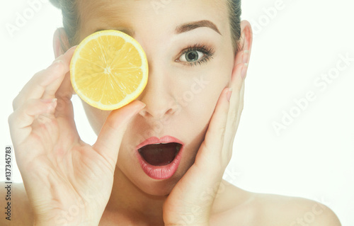 Young woman looking at the photographer through a slice of lemon